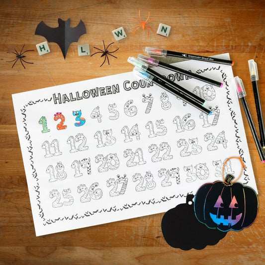 A Halloween Countdown coloring poster with numerical monsters is displayed on a desk with markers and some pumpkin scratch-off art ornaments.