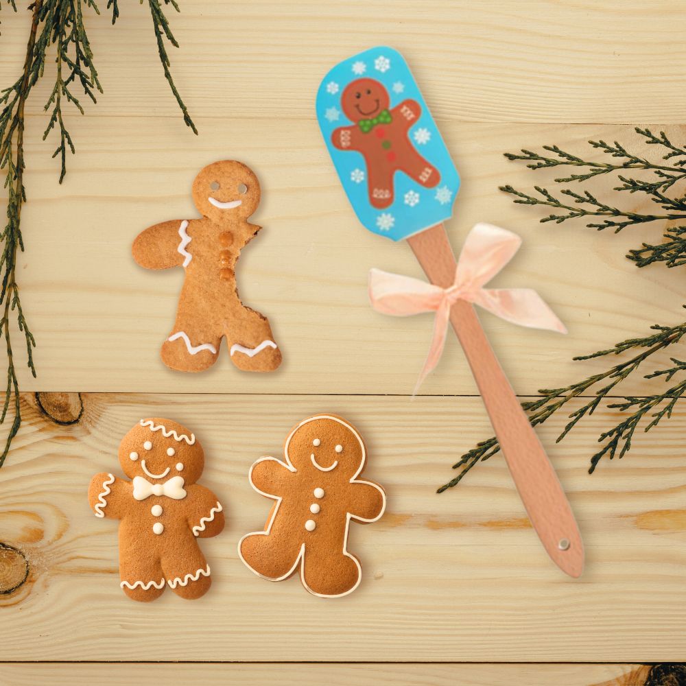 A colorful gingerbread man patterned spatula is displayed with some gingerbread man cookies.