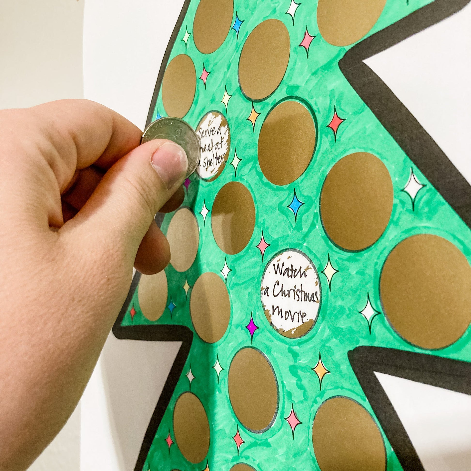 A close up of a woman scratching off one of the gold scratch-off stickers on her Christmas advent poster.
