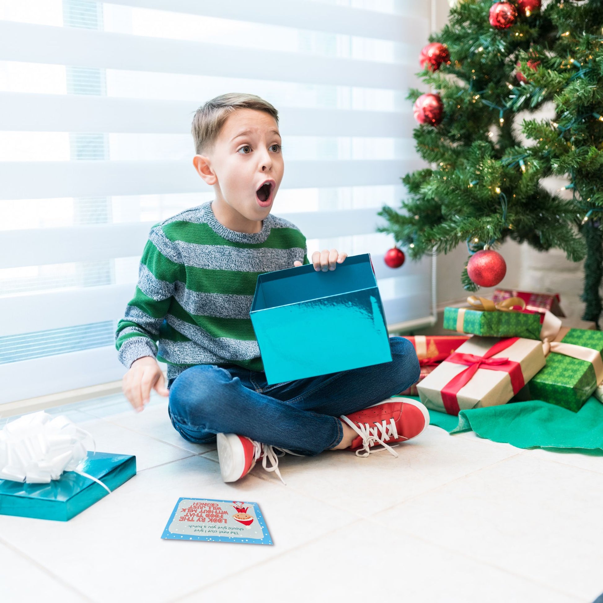 A boy looks up in happy disbelief as he opens the package at the end of a Christmas treasure hunt