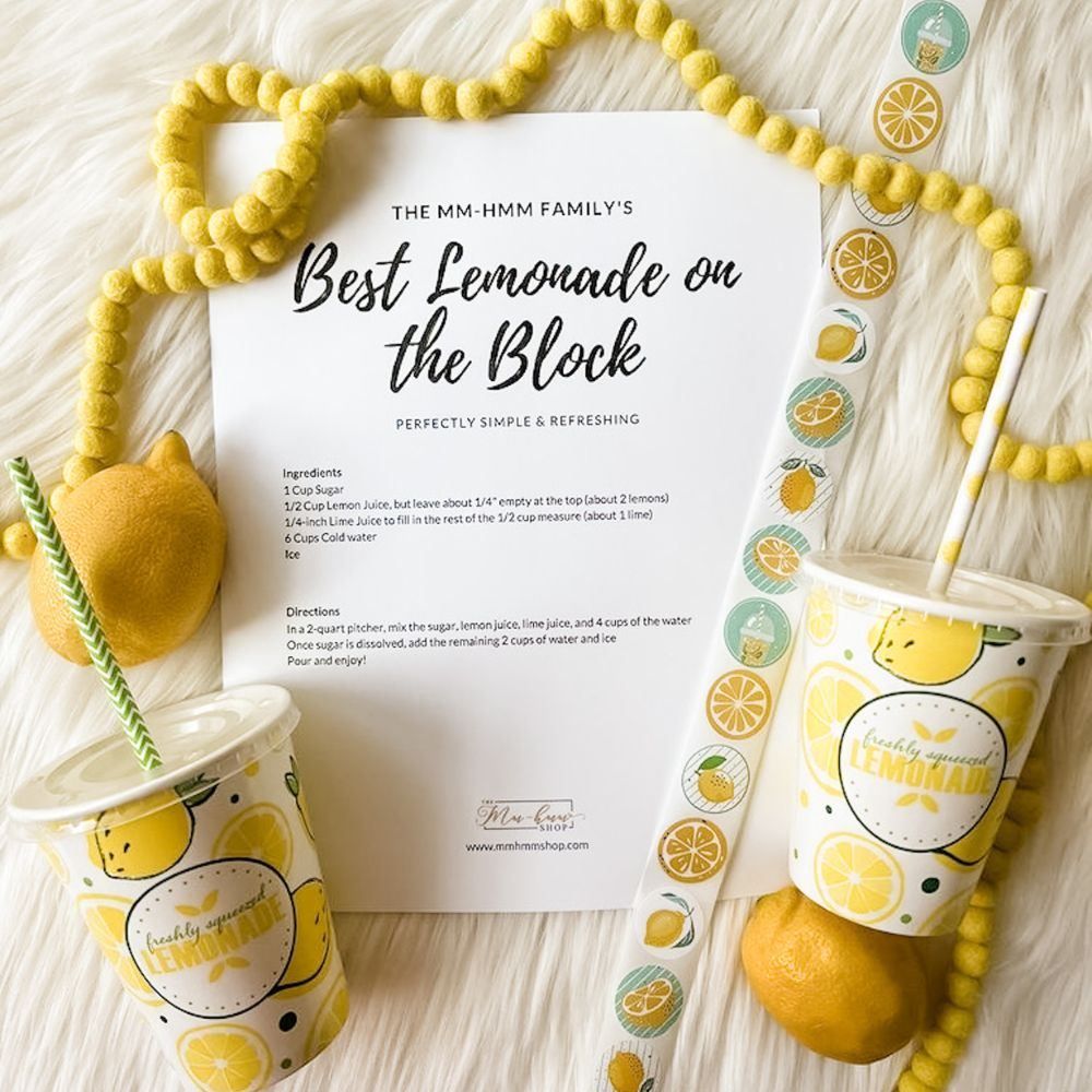 A recipe for The Best Lemonade on the Block is displayed along with paper cups with a lemon/lemonade design and coordinating paper straws.